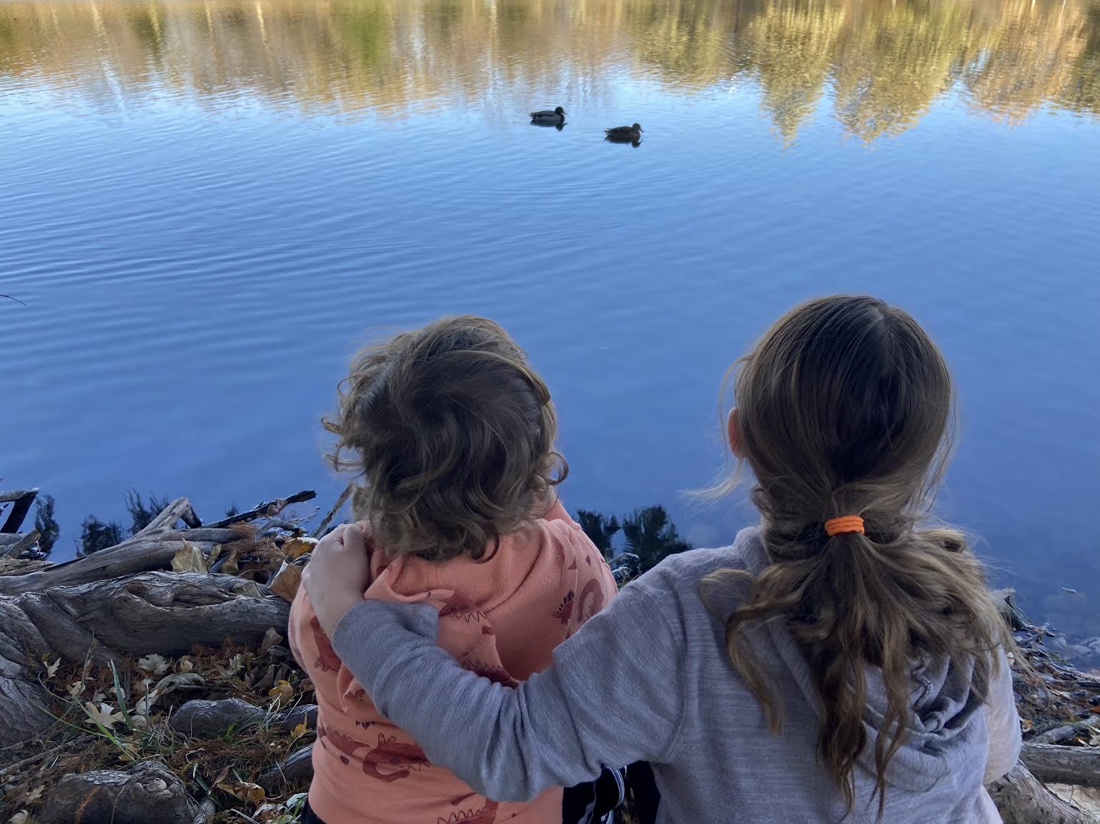 two children looking out on serene water